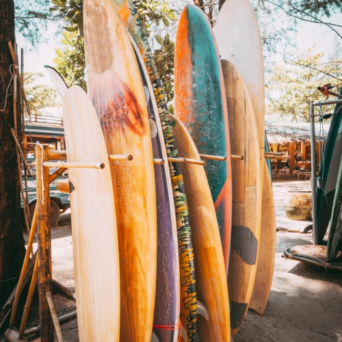 Colorful surfboards standing upright on a rack outdoors near a beach area