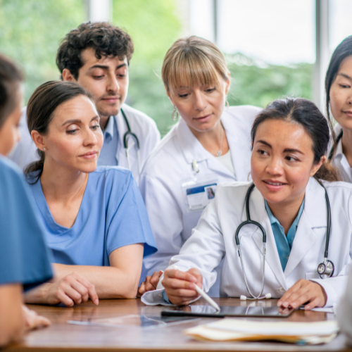 Group of healthcare professionals in scrubs collaborating and reviewing information together in a clinical setting